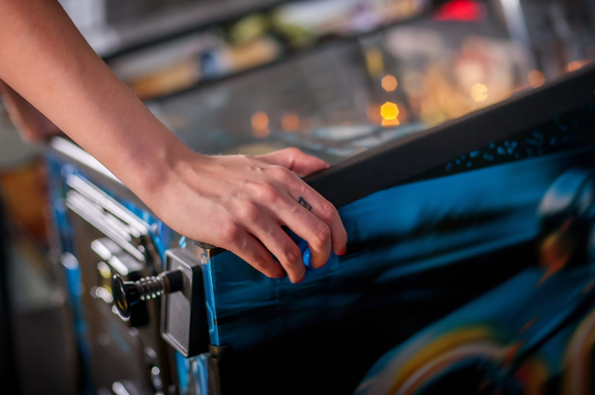 Close up shot of person playing with a pinball machine