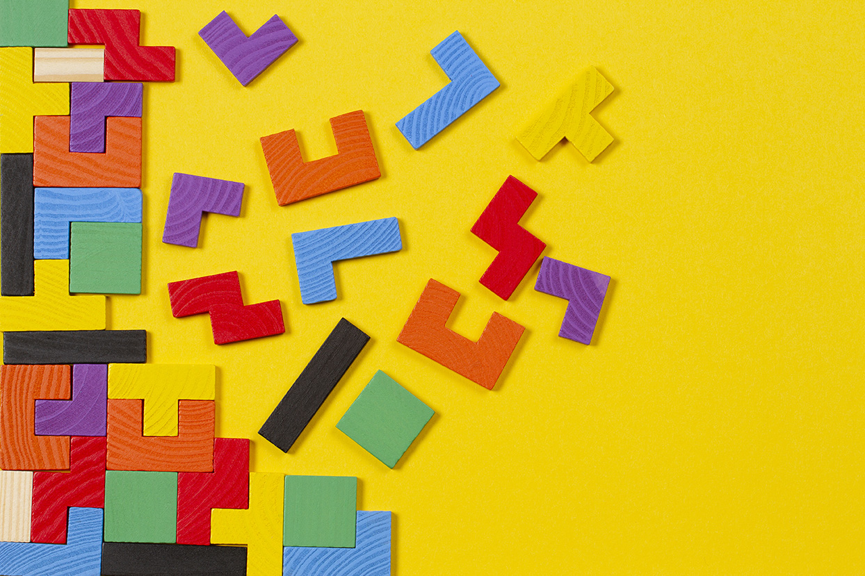 Different colorful shapes wooden blocks on yellow background. Top view